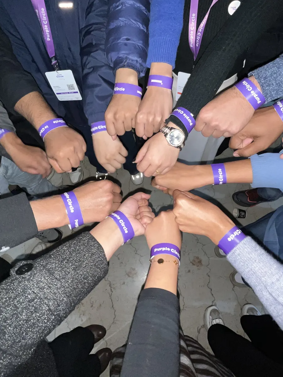 Think Purple Nepal: designers with Purple Circle wristbands, hands together in a circle