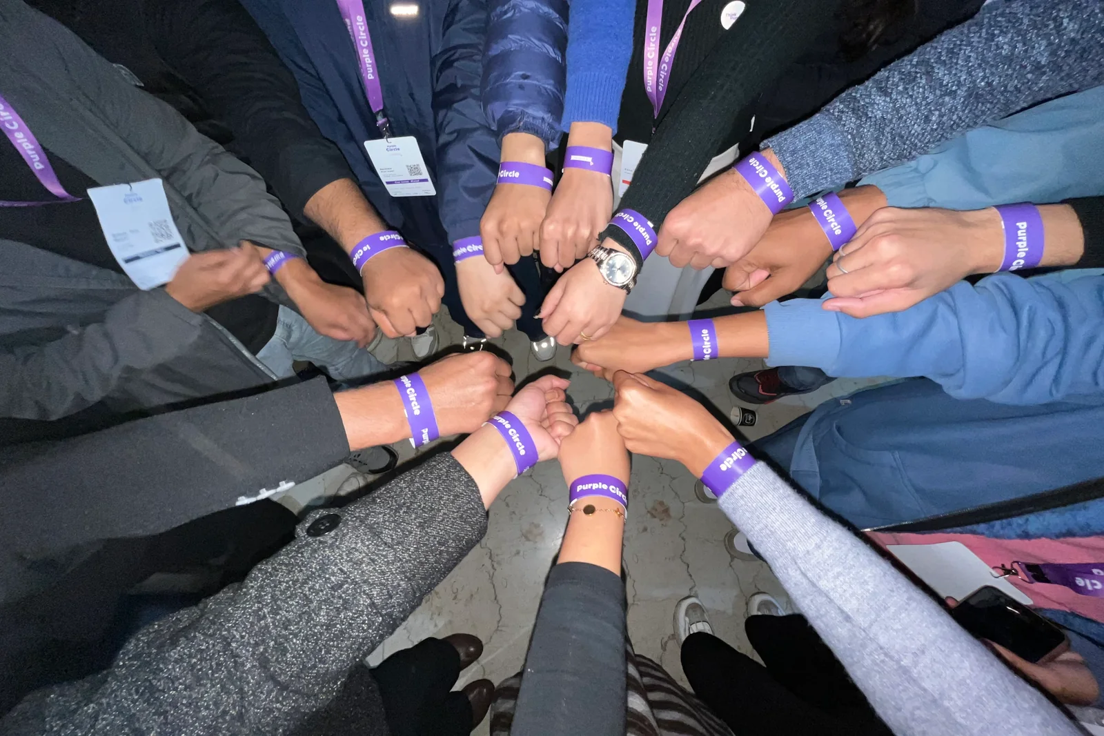 Purple Circle Version 2, Think Purple Nepal: attendees standing in a circle, Purple Circle wristbands on, fists together in the middle